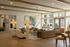 Inviting open-plan living space with elegant wooden beams, plush seating, and abundant natural light streaming through large windows.