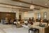 Elegant living space with contemporary leather seating, stylish decor, and warm lighting beneath exposed wooden beams.