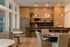 Sophisticated kitchen with sleek wooden cabinets, modern stainless steel appliances, elegant lighting, and a stylish dining area with round tables and cushioned chairs.