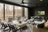 Luxurious screened porch with stylish seating, contemporary ceiling fans, and a wall-mounted TV, offering a serene forest view.