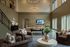 Spacious and inviting recreation room with elegant chandeliers, cozy seating area, ping pong tables, and large windows allowing abundant natural light.