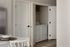 Chic laundry area with modern washer-dryer set neatly tucked behind elegant white doors, complemented by stylish neutral decor.