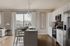 Bright and modern open-concept kitchen and living area with sleek white cabinetry, stainless steel appliances, and a cozy dining nook overlooking a scenic balcony view.