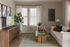 Cozy living room featuring a modern sofa, elegant wooden coffee table, vibrant greenery, and stylish wall art, exuding a welcoming ambiance.