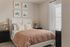 Inviting bedroom with elegant decor, featuring a cozy bed with plush pillows, warm earth-toned bedding, and stylish wicker lamps on sleek black nightstands.