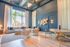 Sophisticated living space with high ceilings, large windows showcasing palm views, elegant decor, and cozy seating arrangement.