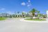 Modern apartment complex with lush palm trees, vibrant landscaping, and clear blue skies, offering a welcoming entrance and ample parking.