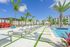 Luxurious apartment poolside oasis with modern loungers, vibrant palm trees, and bright blue skies.