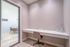Modern minimalist workspace with sleek desk and comfortable chair, featuring elegant glass decor and a view into a cozy meeting area.