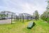 Inviting apartment complex with well-maintained green space, perfect for relaxation and outdoor activities, featuring secure fencing and convenient parking.