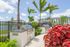 Luxurious outdoor patio with modern grills, tropical landscaping, and a serene lake view at a stylish apartment complex.