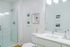 Modern bathroom with a sleek glass-enclosed shower, contemporary white fixtures, and elegant decor featuring framed artwork.