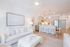 Bright and modern open-concept living area featuring a sleek white sofa, chic kitchen with bar seating, and elegant decor in a serene atmosphere.