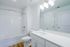 Bright and modern bathroom with sleek white tiles, contemporary lighting, and elegant fixtures.