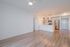 Bright contemporary open-plan kitchen with sleek stainless steel appliances and elegant wood flooring, perfect for modern living.