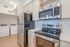 Modern kitchen with stainless steel appliances, sleek cabinetry, and a cozy laundry area featuring washer and dryer, all set on elegant hardwood floors.