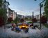 Charming outdoor seating area with a cozy fire pit surrounded by modern apartments and lush greenery at sunset.