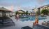 Luxurious apartment community with a sparkling swimming pool, stylish lounge chairs, and elegant architecture under a breathtaking sky.