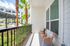 Charming apartment balcony with modern chairs, table, and lush garden view featuring palm trees and vibrant greenery.