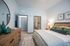 Inviting bedroom interior featuring a cozy bed with textured linens, stylish dresser, and decorative mirror, leading to an en-suite bathroom with modern fixtures.