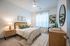 Inviting bedroom with elegant decor, featuring a cozy bed with stylish pillows, chic bedside lamps, and natural light streaming through sheer curtains.
