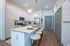 Modern apartment kitchen with sleek white cabinetry, a large island with bar seating, stainless steel appliances, and stylish pendant lighting.