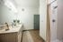 Elegant bathroom featuring a modern vanity with twin sinks, chic wall lights, and a spacious shower with stylish tile design.