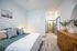 Inviting bedroom with modern decor, wooden dresser, plush bedding, and a cozy ambiance leading to a bright bathroom.