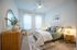 Inviting bedroom with elegant decor featuring a comfy bed, stylish bedside lamps, and a chic wooden dresser accented by a lush plant.