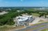 Aerial view of a modern apartment complex nestled in lush greenery, offering ample parking and easy highway access.