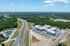 Aerial view of a modern apartment complex surrounded by lush greenery, with convenient highway access and spacious parking.