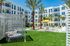 Luxurious apartment exterior with sunny poolside, palm trees, and stylish cabana seating.