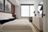 Elegant bedroom featuring a stylish bed with plush bedding, modern dresser with golden handles, and large window flooding the space with natural light.