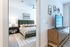 Inviting bedroom featuring a plush queen bed with modern decor, adjacent to a stylish wooden dresser with a mounted flatscreen TV.