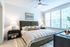 Inviting bedroom with large windows, plush bed, stylish decor, and modern ceiling fan creating a serene retreat.