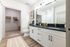 Elegant bathroom with sleek white cabinetry, spacious vanity, and inviting walk-in closet.