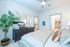 Inviting bedroom interior showcasing cozy bed, stylish dresser with decorative accents, elegant wall mirrors, and a lush indoor plant, leading to a bright walk-in closet.
