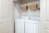 Modern laundry room with vibrant white washer and dryer, featuring stylish storage baskets for a clean, organized look.