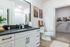 Modern bathroom with elegant white cabinetry, sleek black countertop, and adjoining walk-in closet, showcasing stylish decor and ample storage.