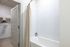 Modern bathroom with a clean white bathtub, elegant curtain, and walk-in closet access offering convenience and style.