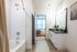 Modern bathroom with sleek vanity and inviting tub, leading to a cozy bedroom with natural light.