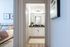 Modern apartment view showcasing a serene bedroom with elegant decor leading into a sleek bathroom with white cabinetry and stylish fixtures.