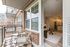 Chic apartment balcony with stylish wicker chairs overlooking modern open-concept living and kitchen area.