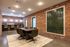 Chic communal space with exposed brick walls, elegant lighting, and stylish seating around a wooden table, perfect for collaborative meetings.