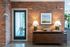 Chic apartment entrance featuring exposed brick walls, modern mid-century furniture, and elegant lighting accents.