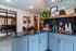 Modern kitchen with elegant black granite countertop, stylish shelving with greenery, and an inviting dining area overlooking a chic conference room.