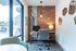 Chic home office with exposed brick wall, modern desk, and large window offering natural light.