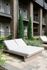 Chic apartment patio with modern brick facade, featuring elegant outdoor lounge chairs and lush landscaping for a relaxing retreat.