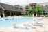 Luxurious apartment complex with a pristine pool, chic lounge chairs, and lush landscaping, promising a serene living experience.