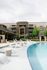 Luxurious apartment complex with a sleek swimming pool, elegant lounge chairs, and lush greenery for a tranquil lifestyle.